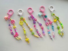 several different colored beads and key chains on a white surface with scissors in the foreground