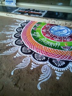 a colorful rangolite design on the ground in front of a storefront window