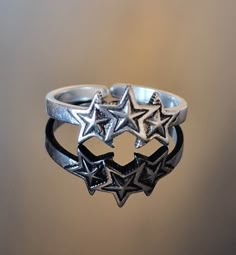 This sterling silver 925 row of 3 stars is very comfortable to wear, these boho rings are minimalist and both eye catching, they come gift wrapped and make a wonderful gift for her, either as a Mother's Day gift, birthday gift, anniversary gift, stocking filler or treat yourself. Stars are symbolic of divinity with a belief being that the countless stars we see in the distance are fallen angels cast out from heaven. For this reason, stars can often be seen referenced as divine light. In general, Star Themed Christmas Gifts, Star Promise Rings, Adjustable Star Midi Rings For Promises, Adjustable Star Midi Rings For Promise, Adjustable Star-shaped Midi Rings, Cool Silver Rings, Star Gifts, Silver Star Ring, Star Rings