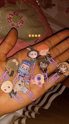 a person's hand with some paper clips on it that are shaped like cartoon characters