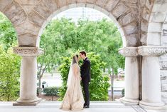 a bride and groom standing under an archway