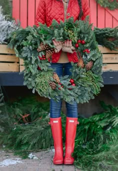 a woman in red jacket and boots holding wreath