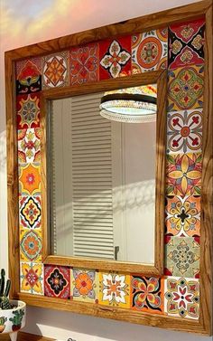 a mirror that is on the side of a wall next to a sink and potted plant