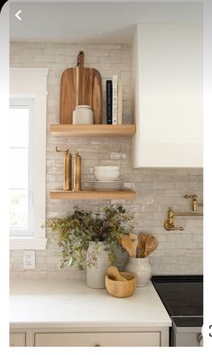 a white kitchen with open shelves and wooden utensils