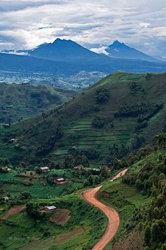 a dirt road winding through a lush green valley