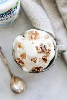 a bowl filled with ice cream and nuts next to a cup of yogurt