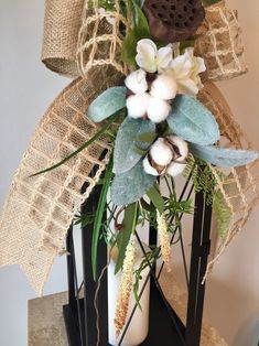 a vase filled with flowers and greenery sitting on top of a table next to burlap