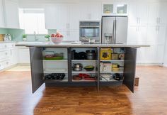 an open kitchen with stainless steel appliances and wood flooring in the middle of it