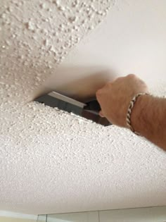 a person is painting the ceiling with white paint