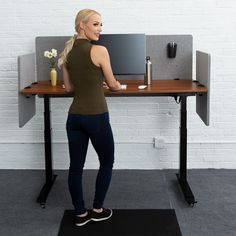 a woman standing in front of a desk with a computer monitor and keyboard on it