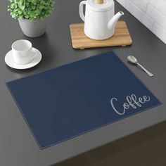 a blue placemat with the word coffee on it next to a cup and saucer