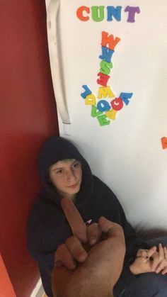 two children sitting on the floor in front of a refrigerator with letters written on it