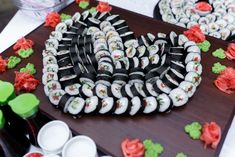 sushi rolls are arranged in the shape of a heart on a wooden platter