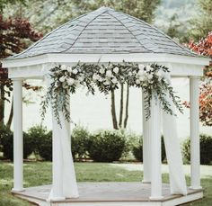 a white gazebo decorated with flowers and greenery