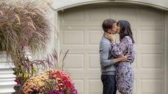 a man and woman kissing in front of a garage