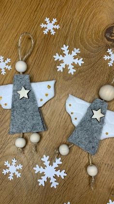 two felt angel ornaments on a wooden table with snowflakes and stars in the background