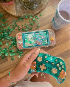 a person holding a nintendo wii game controller next to a table with plants on it