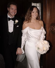 a bride and groom are holding hands as they walk into the room together in tuxedos