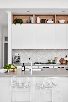 two white chairs sitting in front of a kitchen counter