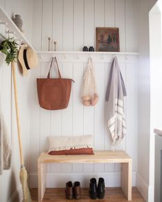 a wooden bench sitting next to a white wall with shoes on it's shelf