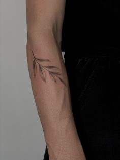 a woman's arm with a tattoo on it that has an olive branch in the middle