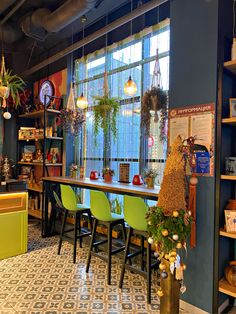 a room filled with lots of green chairs and plants on top of a wooden table