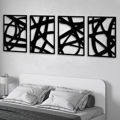 three black and white paintings on the wall above a bed