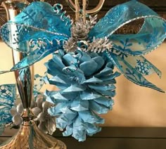 a blue and silver christmas ornament sitting on top of a metal stand next to a mirror