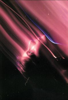 a blurry image of pink and blue lights in the night sky, with dark clouds