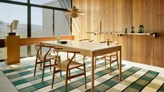 a dining room table and chairs in front of a large window with wooden paneling