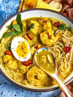 a bowl filled with shrimp and noodles, garnished with an egg