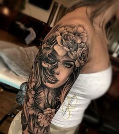 a woman's arm with a skull and flowers on it