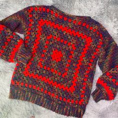 a red and black sweater on top of a white furnishing covered floor next to a pair of scissors