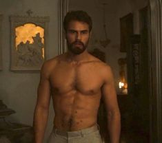 a shirtless man with no shirt standing in front of a mirror and looking at the camera