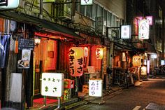 an alley way with signs and lights on the side of it at night time in japan