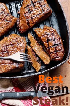 the steaks are being cooked on the grill in the pan with fork and knife