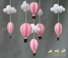 pink and white hot air balloon mobiles hanging from strings with clouds in the background