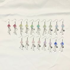 a bunch of earrings that are sitting on a white surface with some beads hanging from them