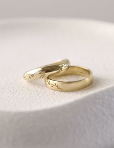 two gold wedding rings sitting on top of each other