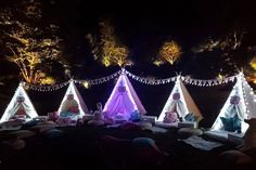 a group of teepee tents lit up at night