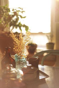 the sun is shining on a table with some cups and saucers in front of it