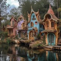 some houses that are by the water in front of trees and bushes, with windows on each side