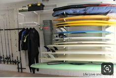 surfboards are stacked on top of each other in a room with white walls and black railings