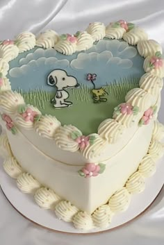 a heart shaped cake with a snoopy dog on it's side and clouds in the background