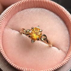 a yellow diamond ring sitting in a pink velvet box