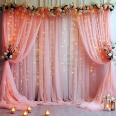 a room with pink curtains and candles on the floor