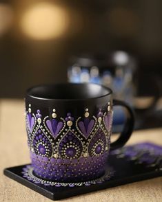 a purple and black coffee cup sitting on top of a coaster