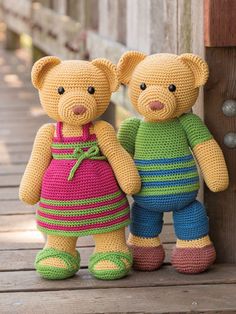 two crocheted teddy bears standing next to each other on a wooden deck,