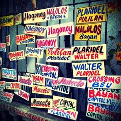 many signs are posted on the side of a building with metal bars and windows behind them