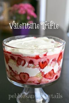 a trifle with strawberries and cream in a glass dish on a black table